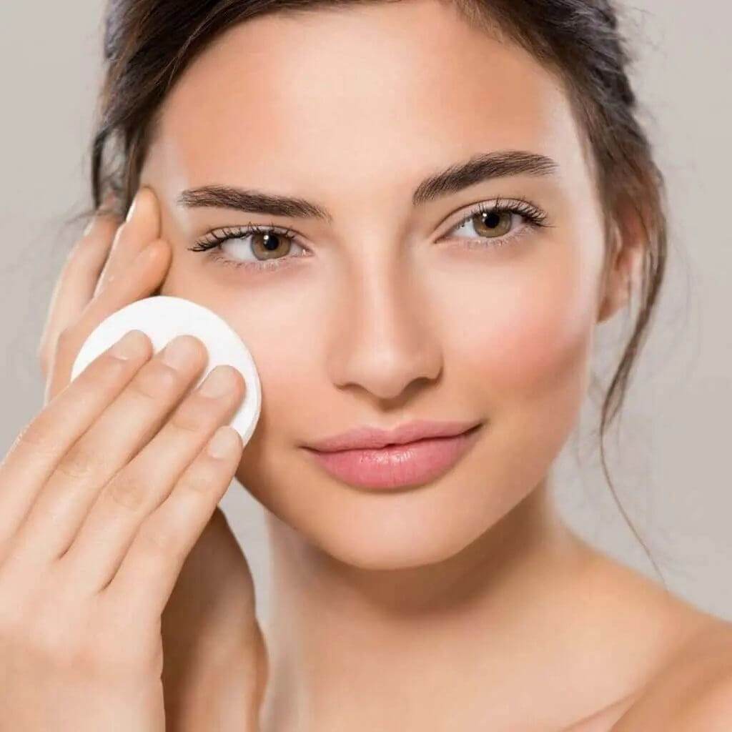 Woman applying skincare product to her face, showcasing healthy skin for essential beauty and skincare tips by pkamazone.