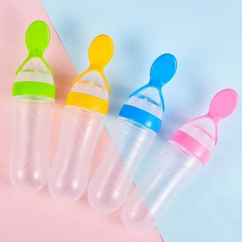 Baby squeezing feeding bottle with soft silicone spoon in various colors on a pastel background.