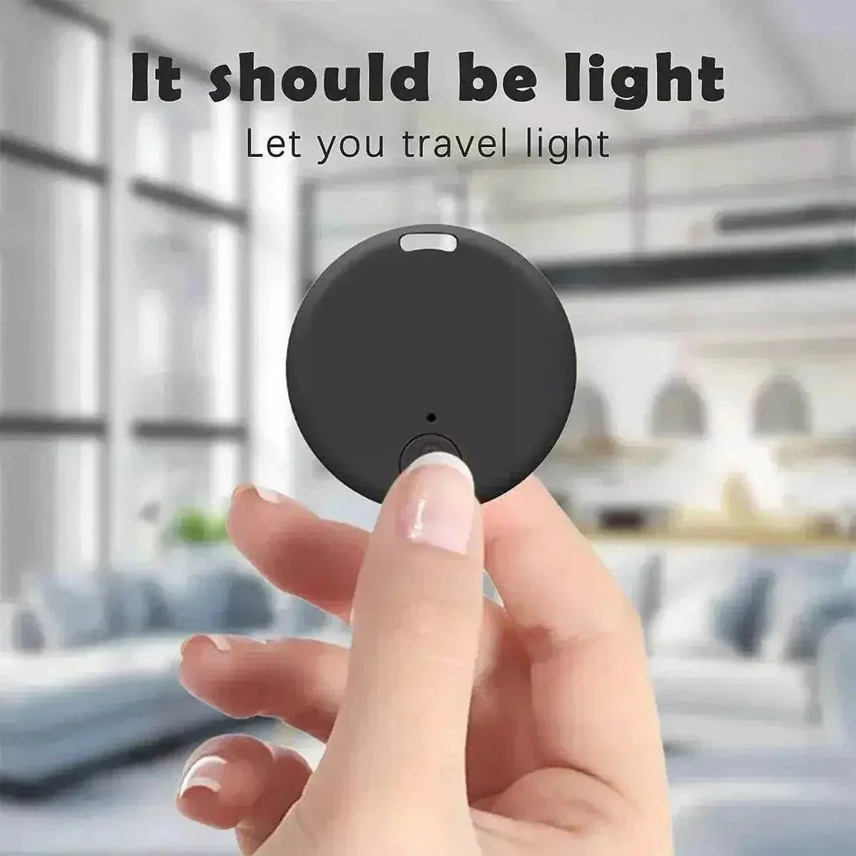 Bluetooth GPS tracking device held between two fingers in a room setting, highlighting its compact design.