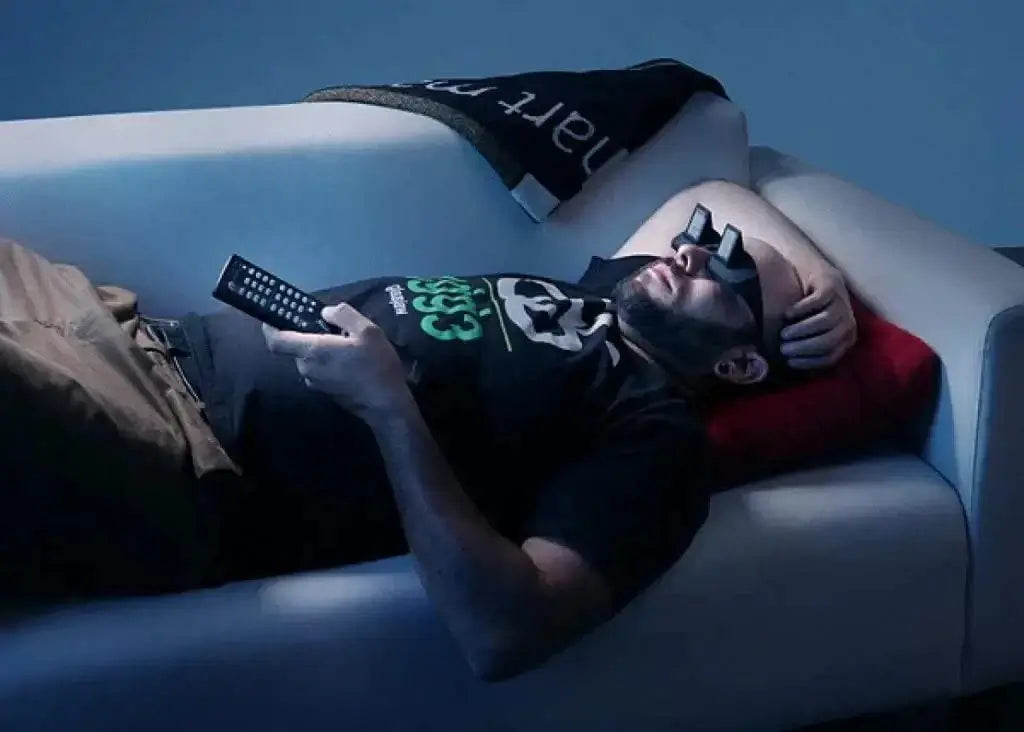 Man relaxing on sofa wearing Lazy Prism Glasses while holding remote, illustrating comfort and productivity.