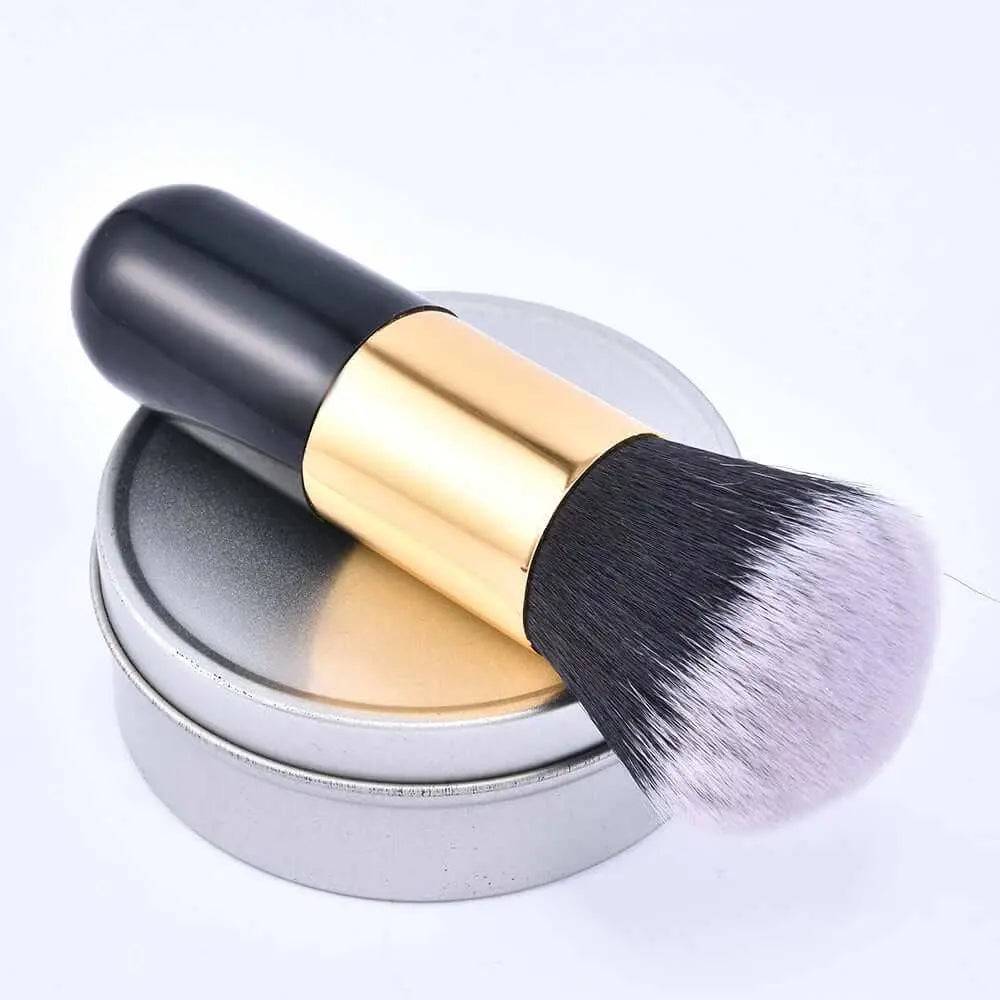 Chubby face makeup brush with black handle and gold ferrule, displayed on a round container lid.