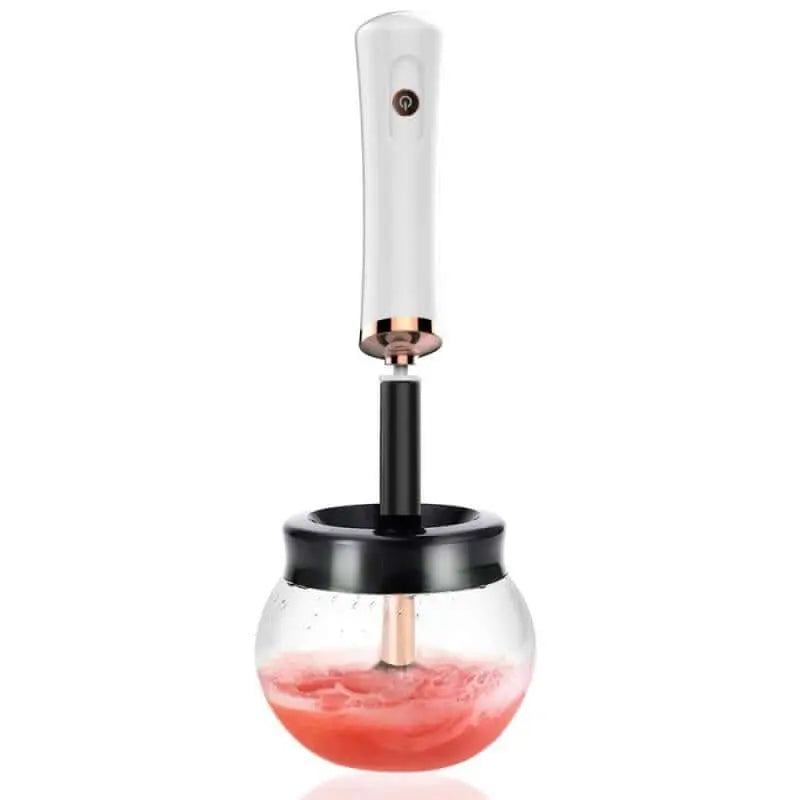 Electric makeup brush cleaning device with a sleek handle in a bowl with pink liquid.