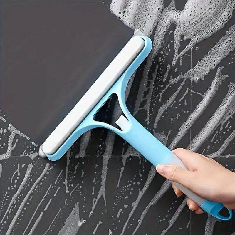 Glass cleaner wiper with scraper in use on soapy glass surface.