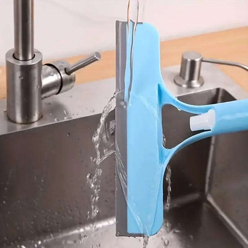 Glass cleaner wiper with scraper and sprayer under running water in a kitchen sink.