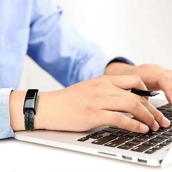 Black braided leather charge and sync cable bracelet worn on wrist while typing on laptop keyboard