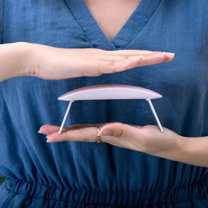 Mini portable LED UV nail dryer held between hands, ideal for fast gel curing.