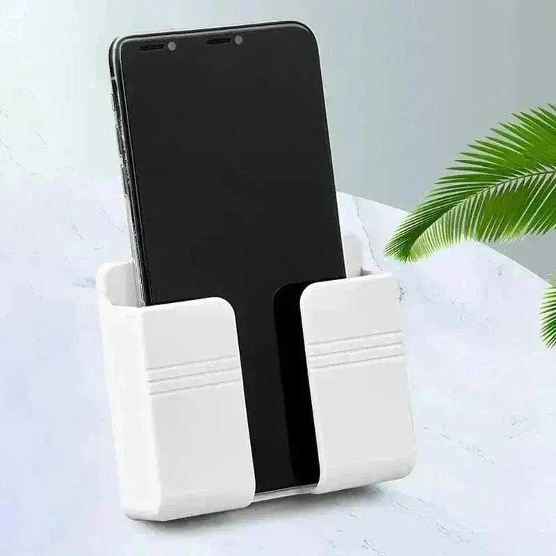 White plastic phone holder with a smartphone, placed on a light surface next to a green leaf.